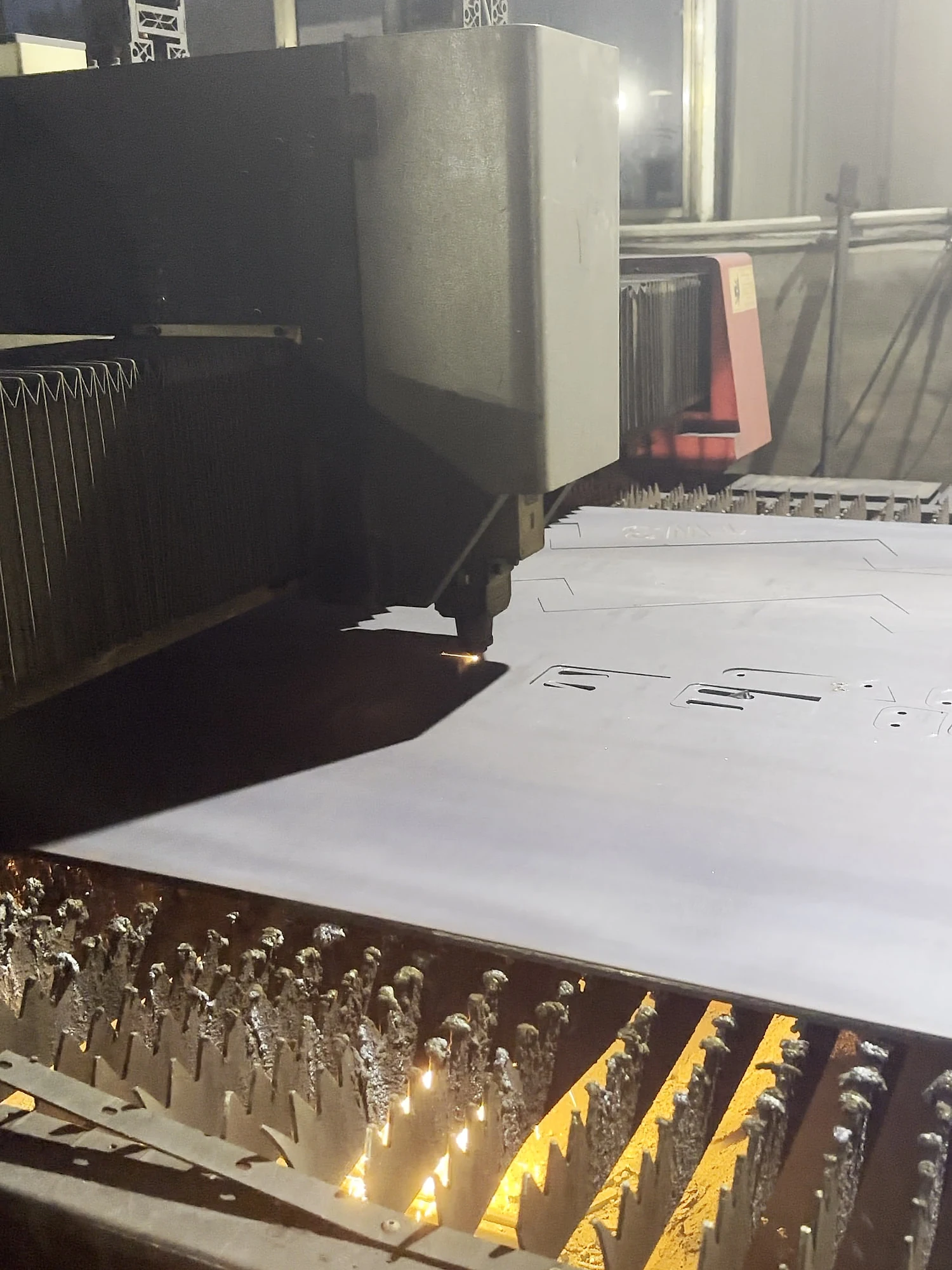 A laser cutting head working on steel plate in the workshop.