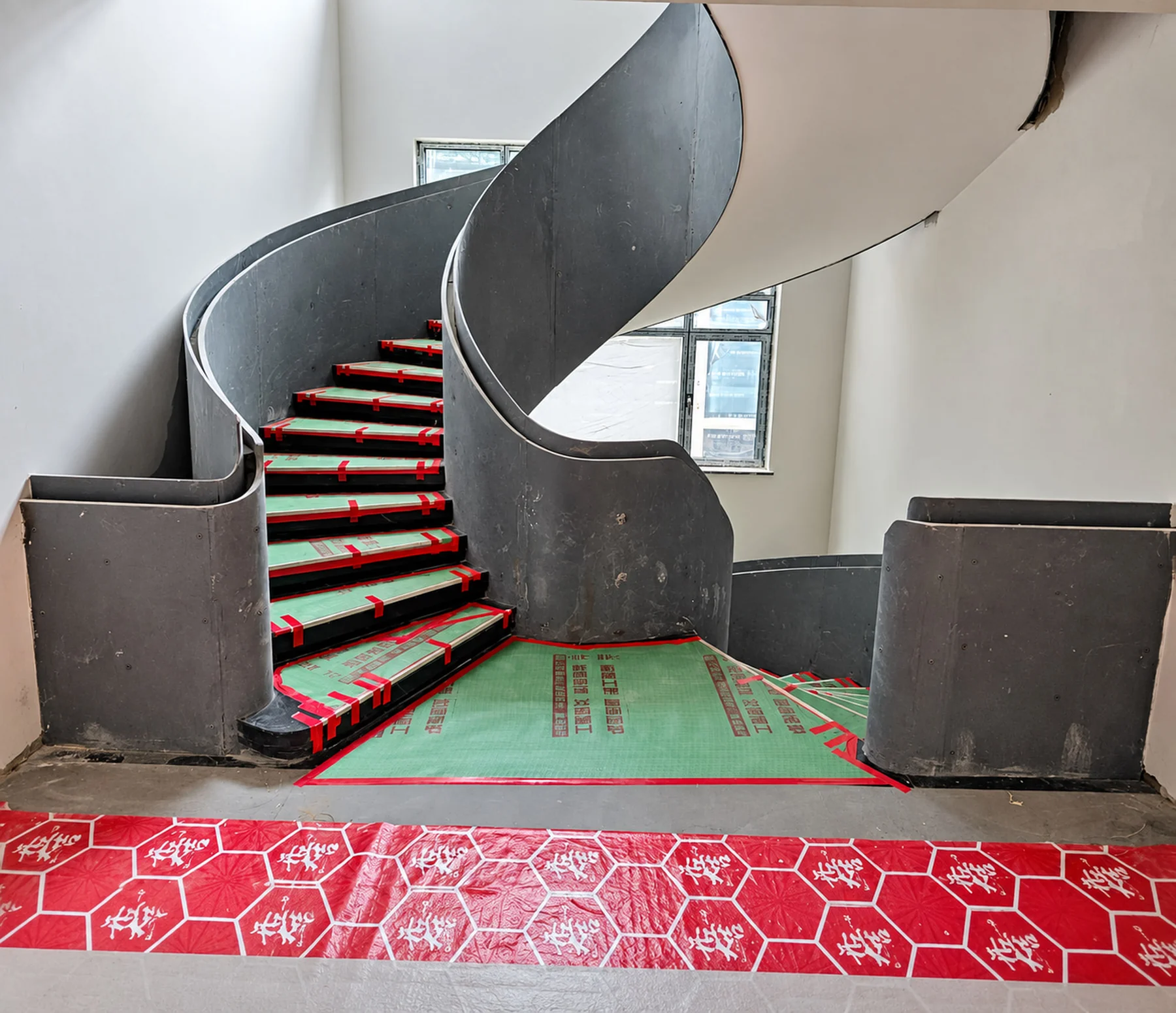 Construction-stage photograph of a curved staircase with protected treads in a private villa in Changde, Hunan, China.