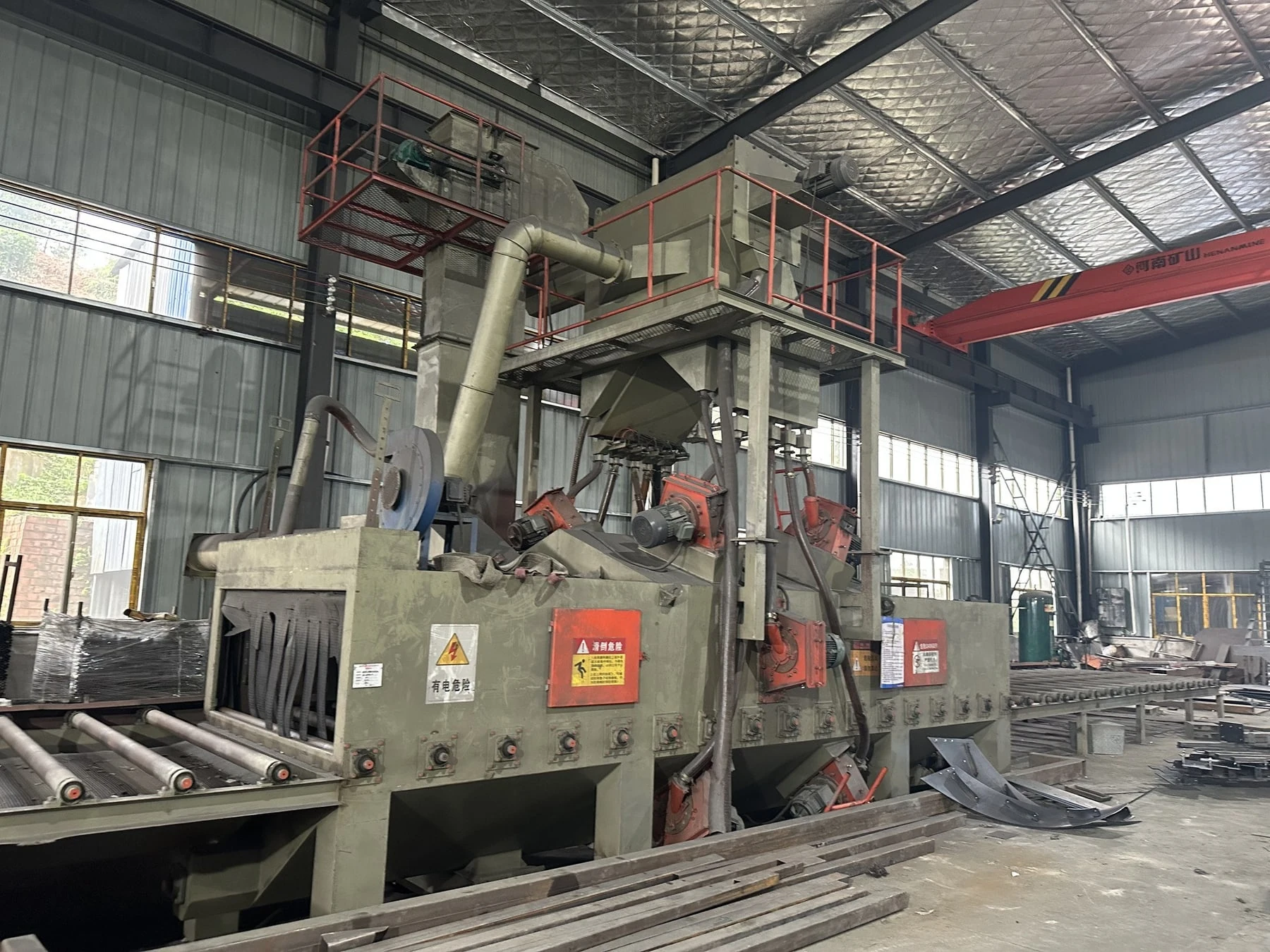 Shot-blasting equipment and roller conveyor inside the steel fabrication workshop.