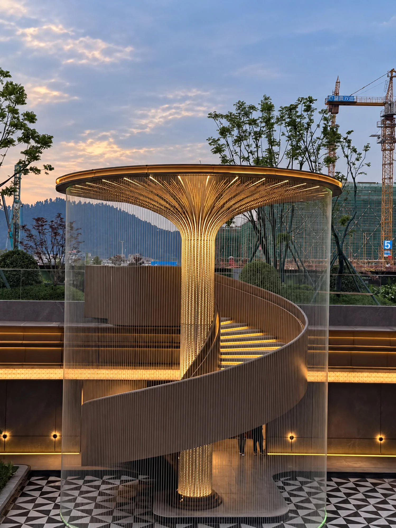 Spiral-form staircase around a central illuminated column with a firework-inspired canopy at Shanghecheng in Liuyang, China.
