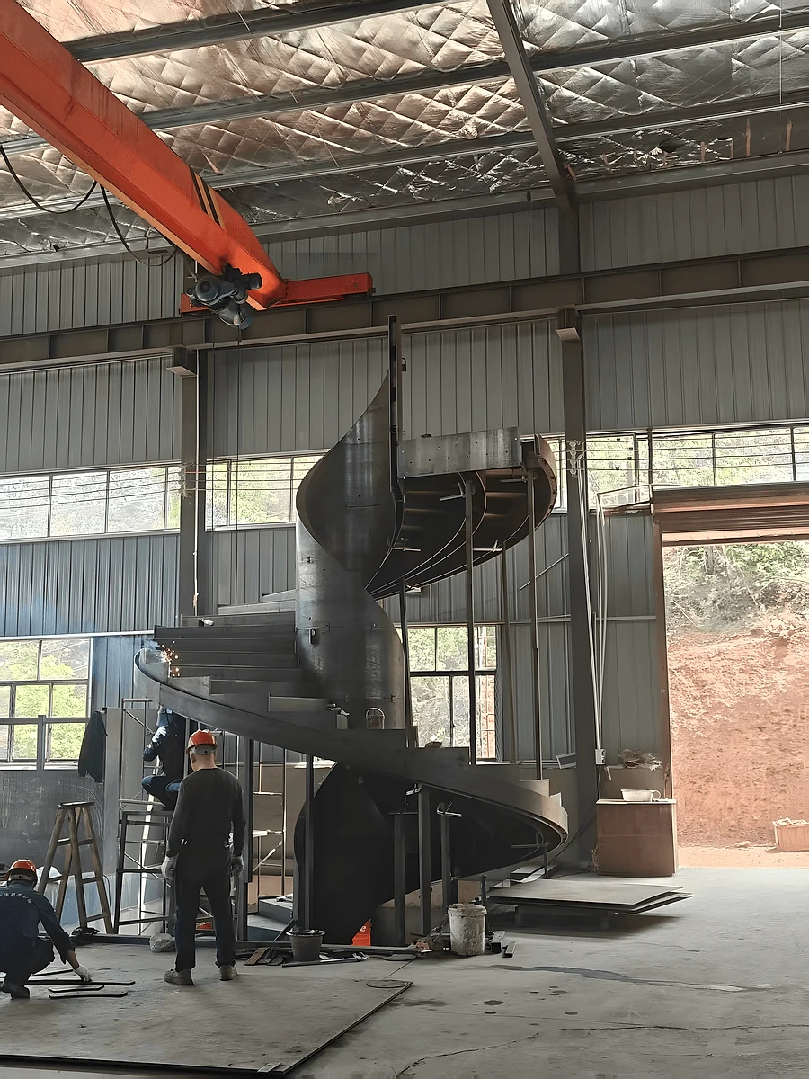 A helical steel staircase assembled inside the workshop before finishing.