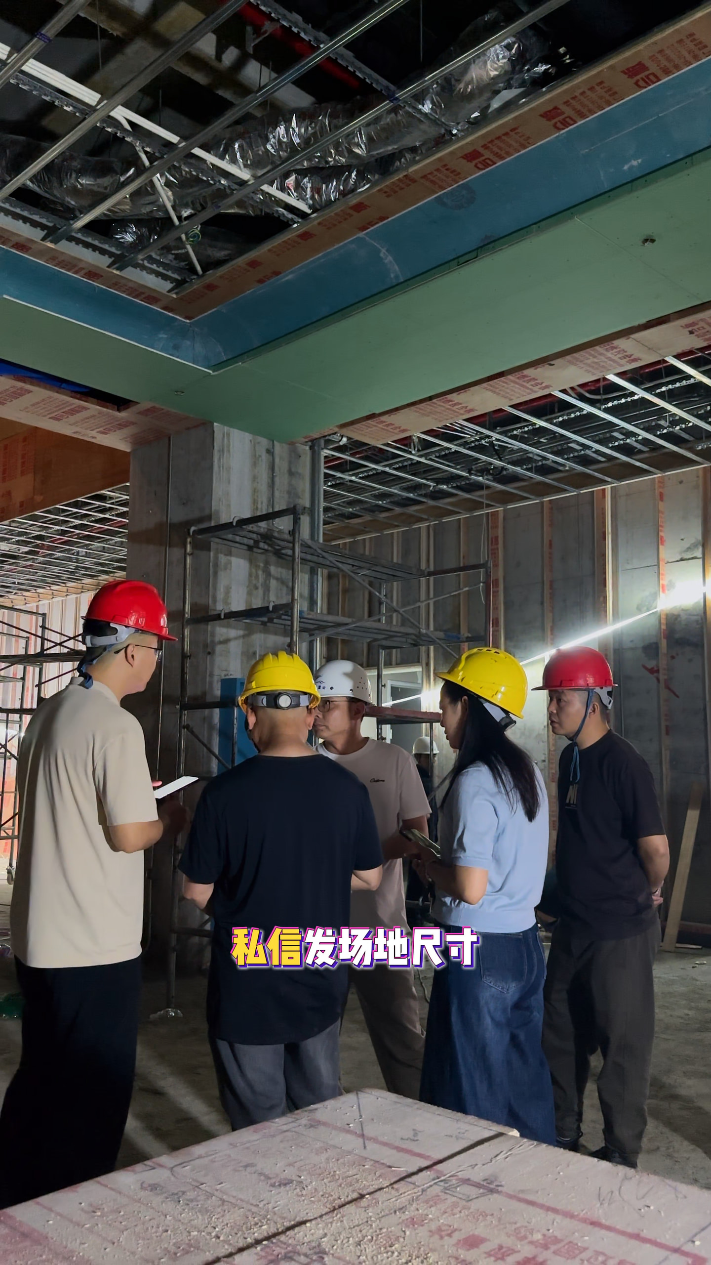 人员戴安全帽在未完成装修的室内现场交流